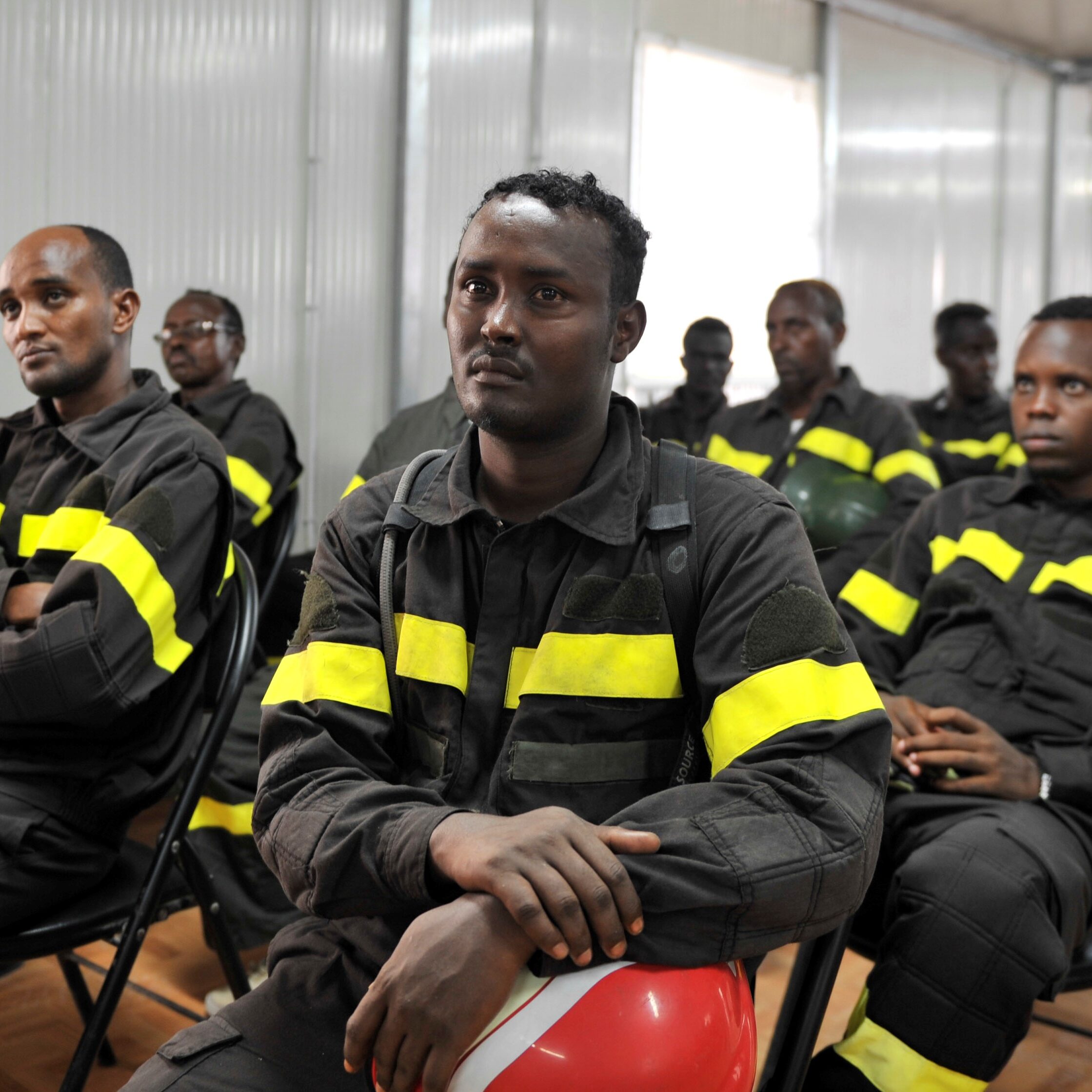 Somali firefighters listen to a trainer during a joint Somali and AMISOM firefighters in a drill conducted upon completion of a refresher training in  aviation fire fighting held in Mogadishu, Somalia on April 21, 2015. After more than two decades of civil war in the country, the Mogadishu Fire Department is once again working on revamping its services in Somalia and this training supported and organised by African Union Mission in Somalia (AMISOM) and United Nations Support Office for AMISOM (UNSOA) is key for capacity building. AMISOM Photo / Ilyas Ahmed